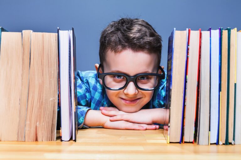 happy-pupil-in-glasses-against-books-PUF3YMT-min
