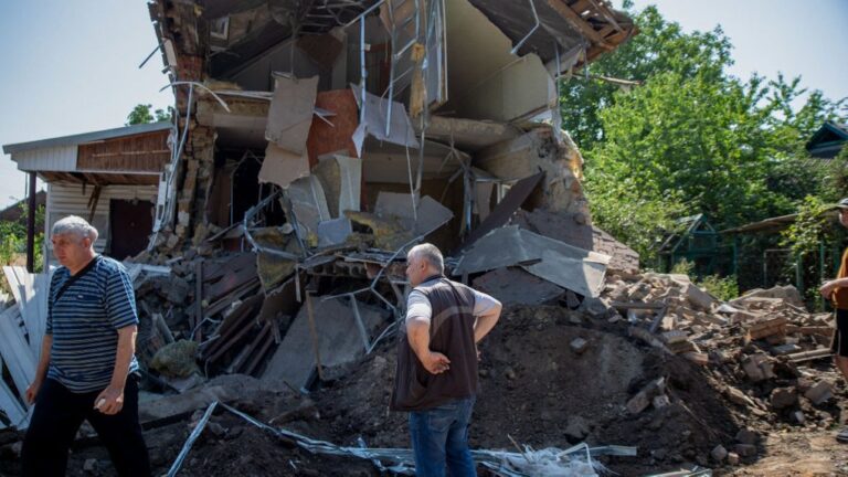 Two men clear rubble after an overnight shelling hits at a