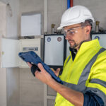 Electrical technician looking focused while working in a switchboard with fuses.