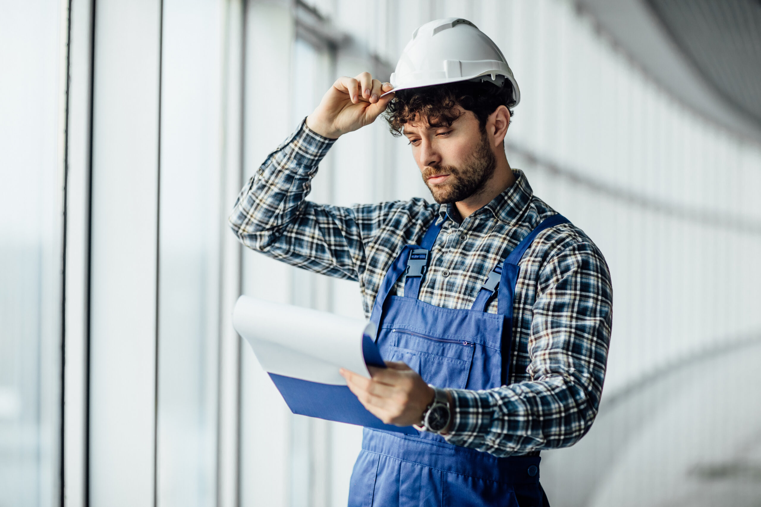 Happy young man architect in hard hat holding folder.