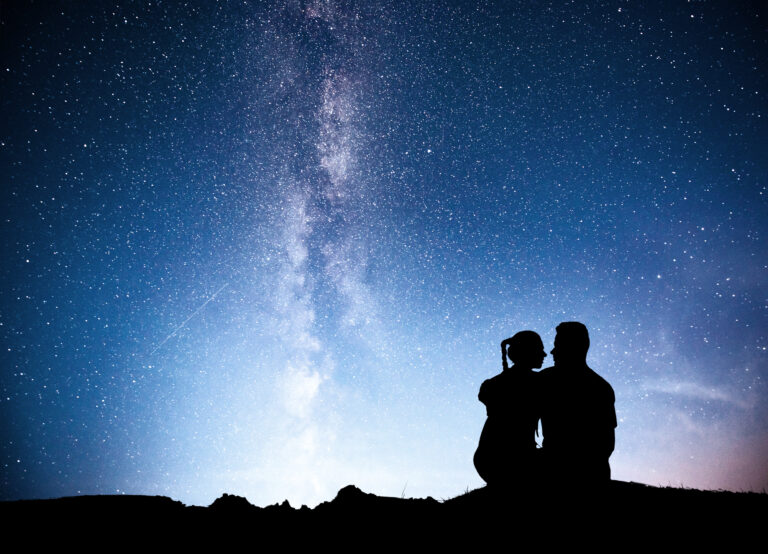 Milky Way with silhouette of people. Landscape with night starry sky. Standing man and woman on the mountain with star light. Hugging couple against purple milky way.