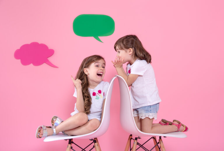 Two little girls on colored background with speech icons