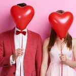Unrecognizable couple with balloon holding hands