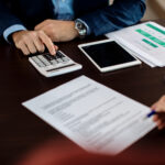 Close-up of real estate agent using calculator while his client