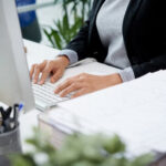 unrecognizable-woman-sitting-at-desk-in-office-and-typing-on-keyboard_1098-20224