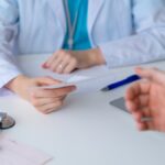 Unrecognizable doctor prescribing pharmacy to patient. Male hand reaching for piece of paper