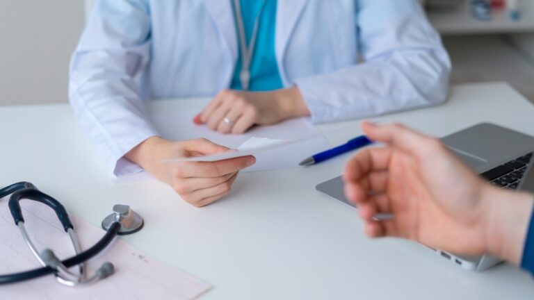 Unrecognizable doctor prescribing pharmacy to patient. Male hand reaching for piece of paper