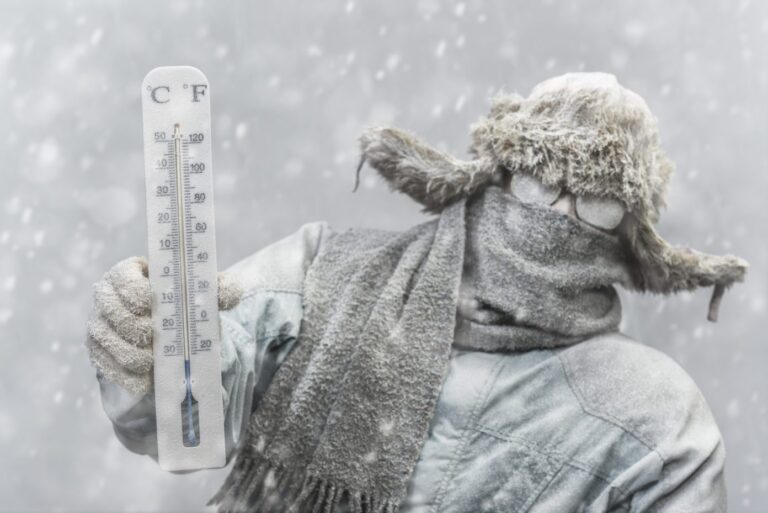Frozen man holding a thermometer while it is snowing