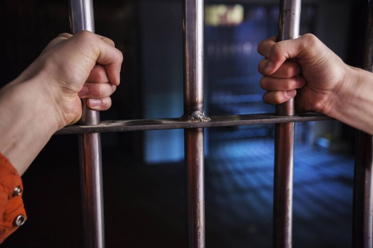 a-man-in-jail-captive-behind-bars-ZTRUSFW-min